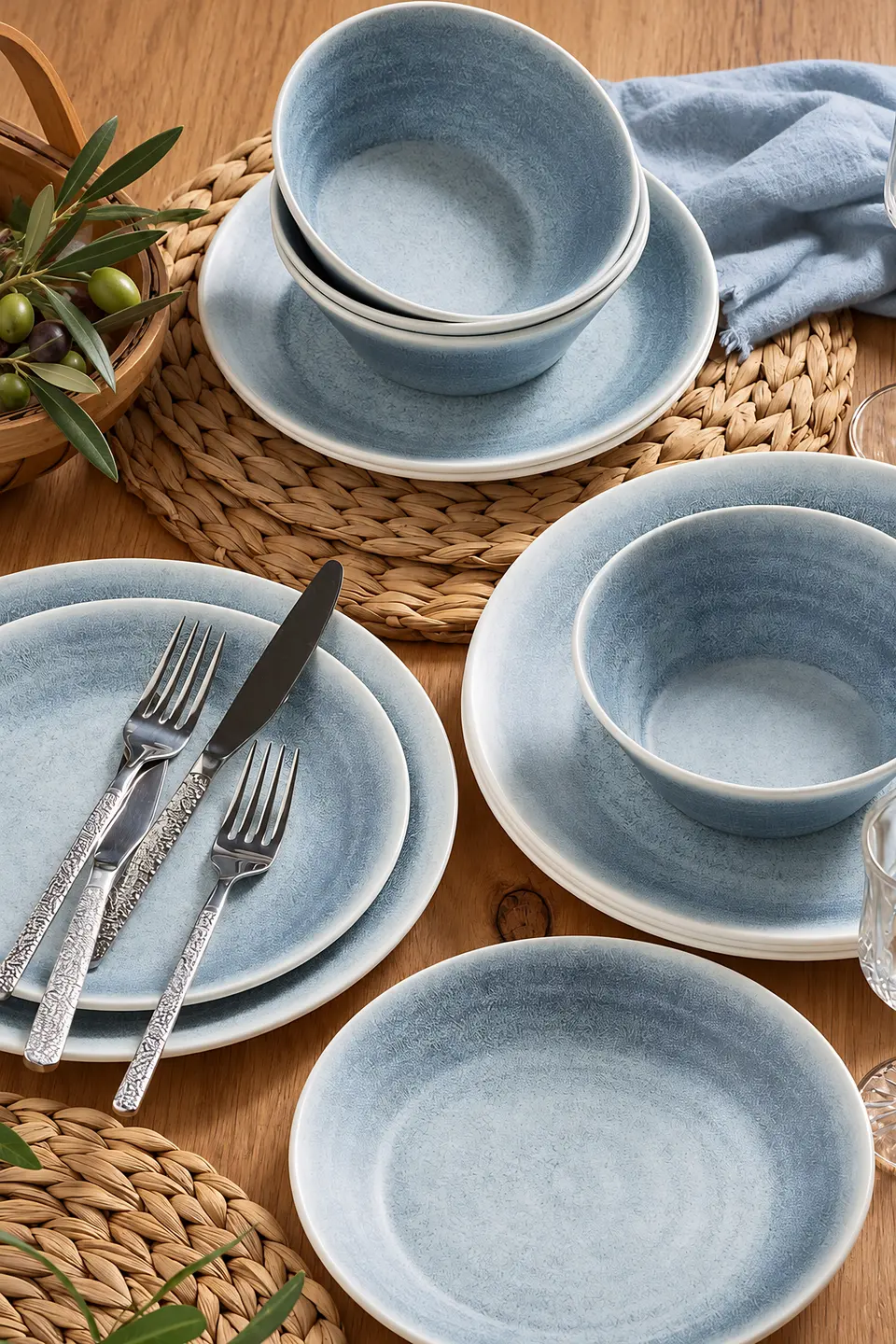Blue speckled plates and bowls with stainless steel cutlery on a wooden table